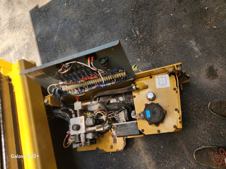 Interior view of a yellow power tool showing exposed circuit board, wiring, springs, and metal components