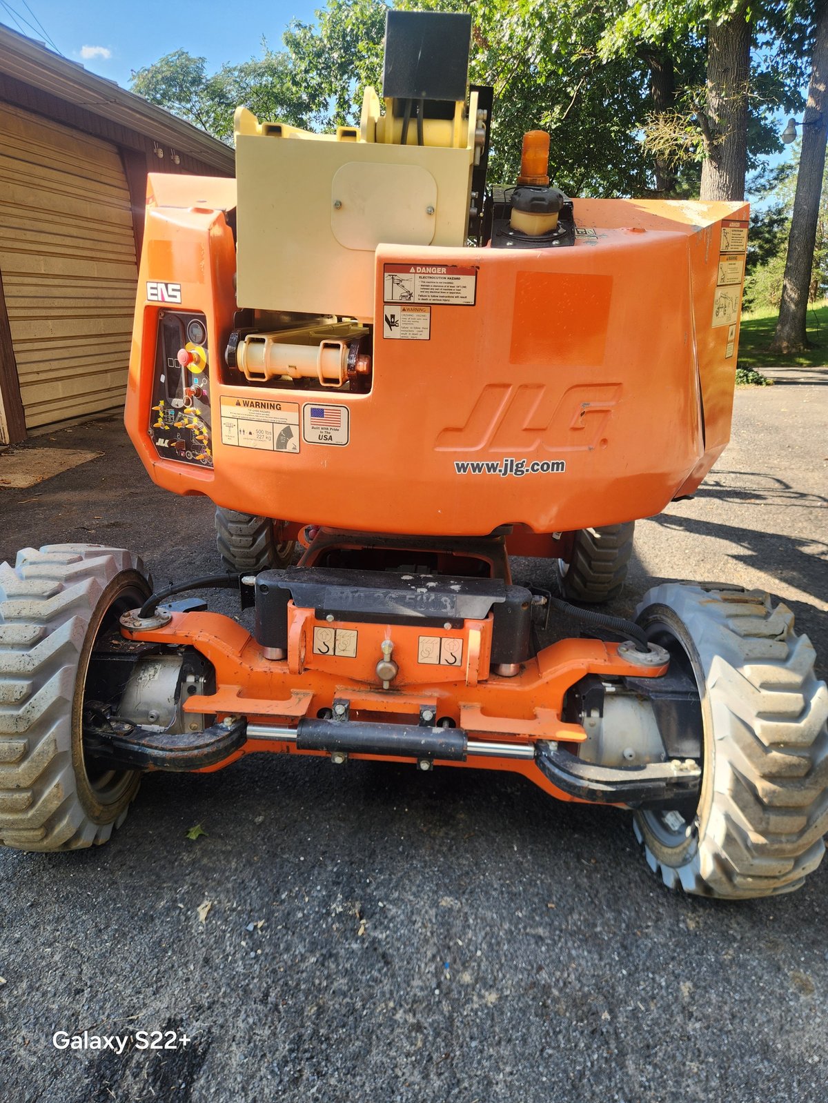 Orange JLG boom lift viewed from front showing articulating arm, control panel, and sturdy wheeled base with wide tires