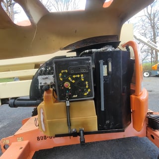 Close-up of orange and tan industrial equipment with control panel showing yellow gauges and switches mounted on the side