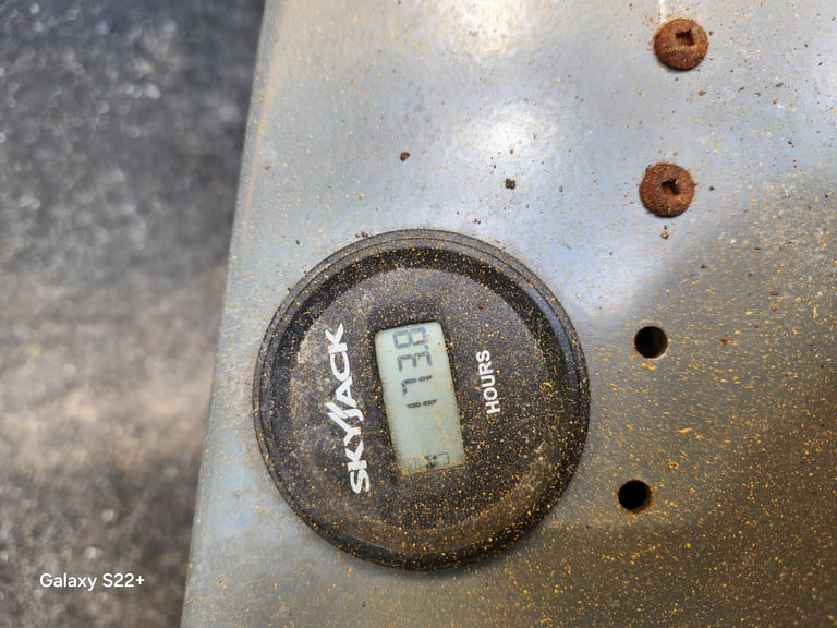 Close-up of a rusted metal surface with a circular logo bearing a temperature reading display, surrounded by various fasteners and holes