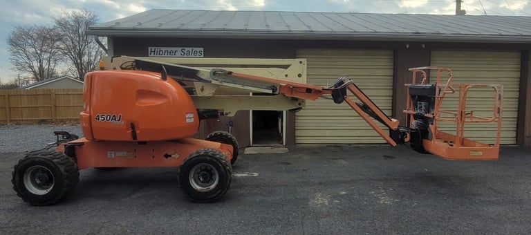 Orange boom lift equipment parked beside warehouse
